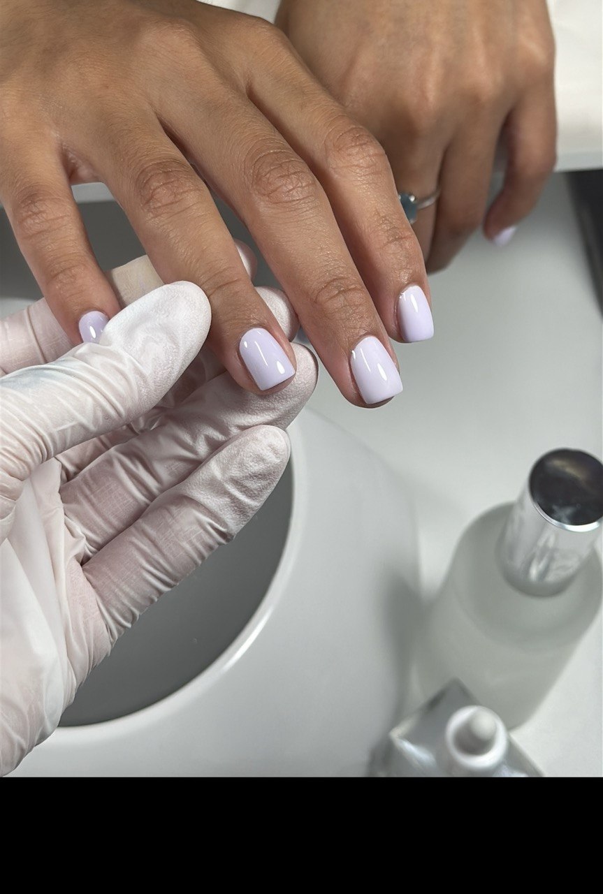 Short white rubber-base manicure being finished in the studio
